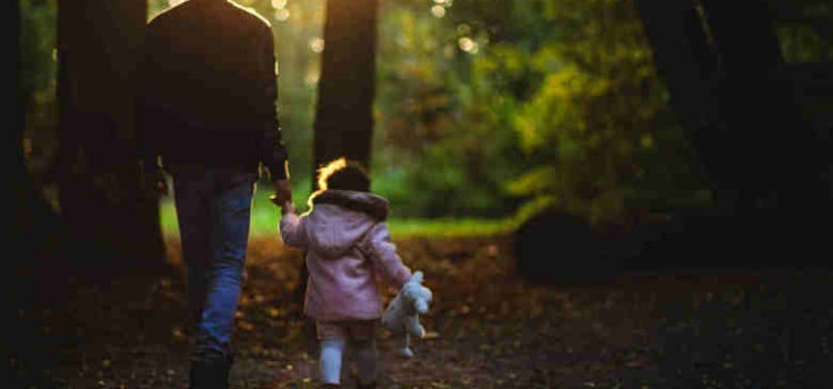 man walking in woods with young daughter